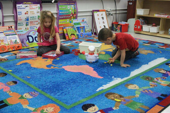 two kids playing on rug with the world on it