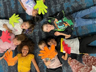 students on ground with paper hands