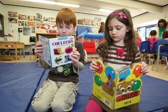 two children reading french books in classroom