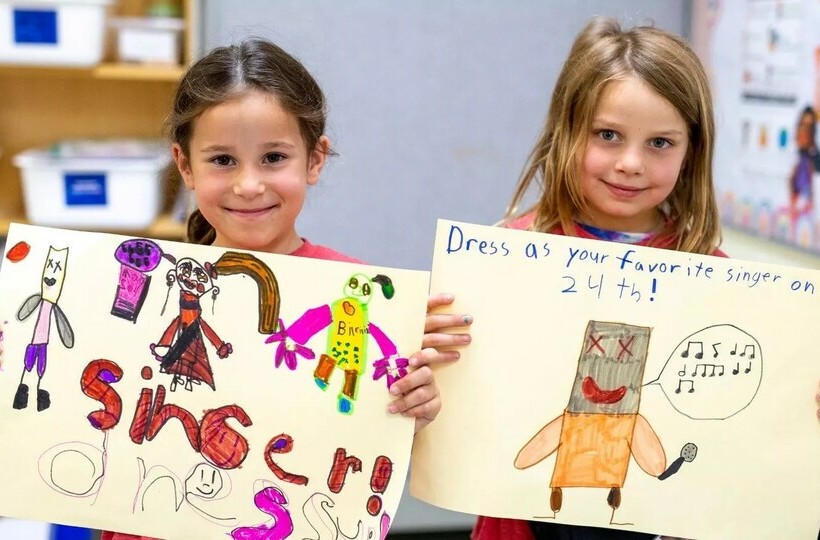 Two grade school students hold up posters they'd drawn up promoting singer dress up.