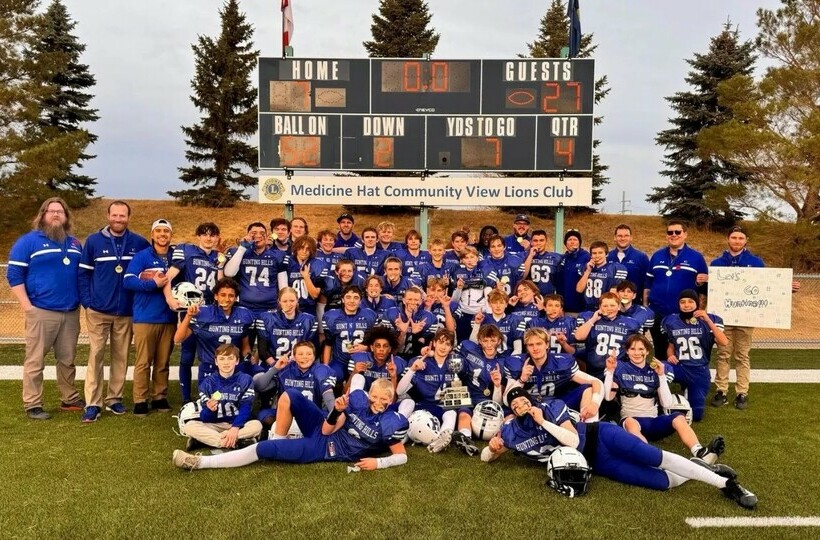 the football team poses on the field in front of the score board.